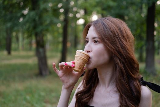 Smiling cheerful ukrainian brunette young woman eating ice cream outdoors