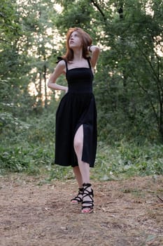 attractive young brunette woman in a black dress posing in the forest. freedom. fashion portrait.