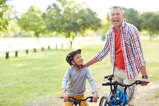 Portrait of a father and son riding bicycles in a park.