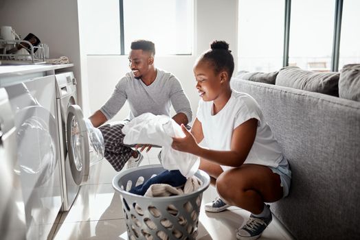Division of labour isnt just for the workplace. Shot of a happy young couple doing laundry together at home.