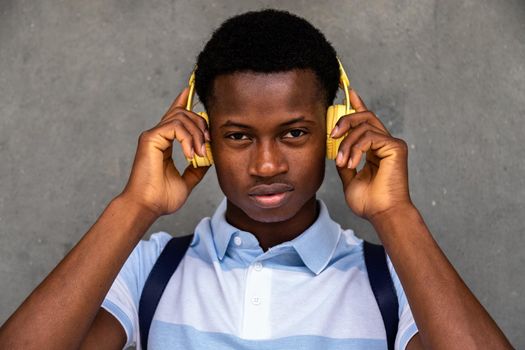 Teenage African American boy looking at camera holding headphones with hands.