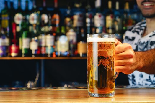 Barman serves glass of cold beer at bar counter in pub
