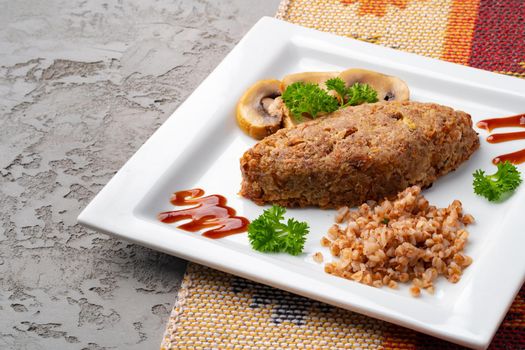 Cutlet with buckwheat with mushrooms on white plate
