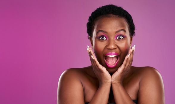 Theres a surprise on the way. Studio shot of a beautiful young woman looking surprised against a pink background.