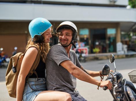 Lets go on an adventure. Shot of two happy backpackers riding a motorcycle through a foreign city.