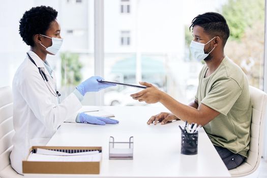 Please fill this out. Cropped shot of an attractive young female doctor handing a clipboard to a male patient during a consult.