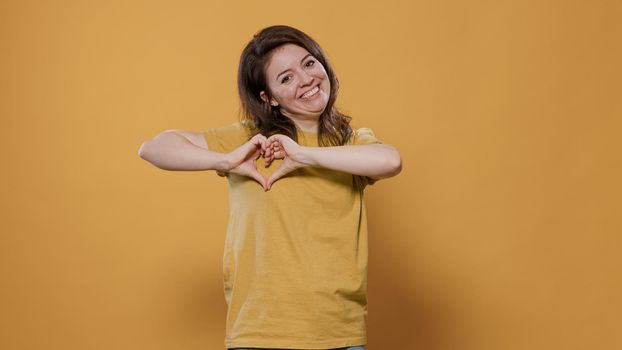 Happy woman gesturing making heart sign with hands to show loving feelings for her partner