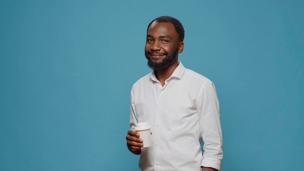 Portrait of male freelancer enjoying cup of coffee in studio