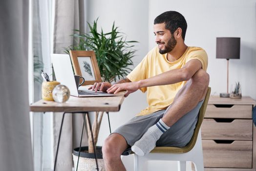 Thank goodness for this work from home gig. Shot of a young man using a laptop while working from home.