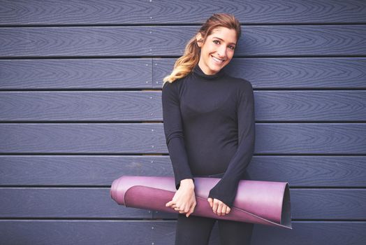 Cropped portrait of an attractive young female athlete carrying her yoga mat.