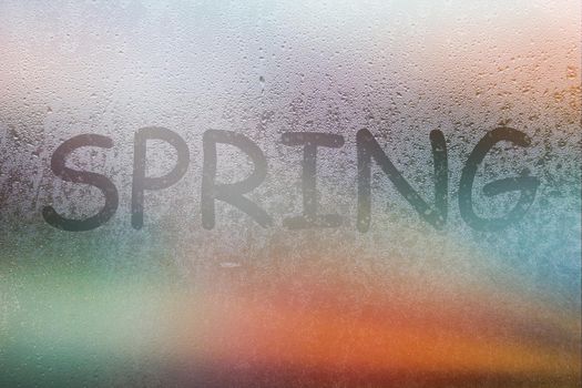 Foggy glass on window with written finger word spring on glass wet orange window in city on sunset