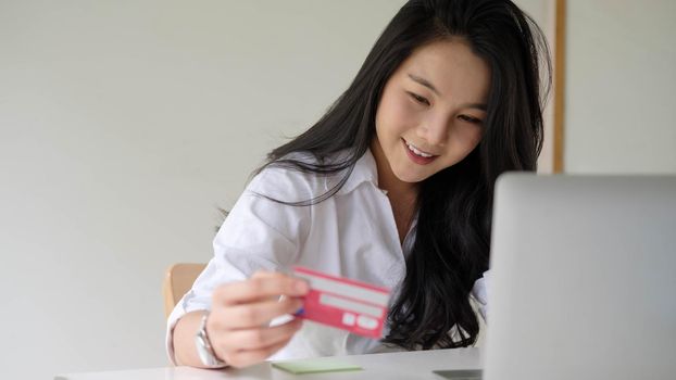Close up woman using credit card for purchasing and shopping online on laptop computer