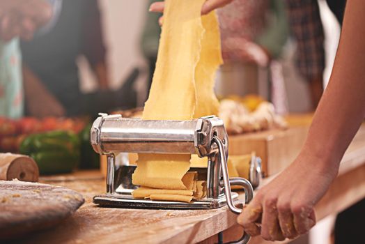 Getting the pasta dish rolling. Cropped shot of a person rolling freshly made dough through a pasta maker.