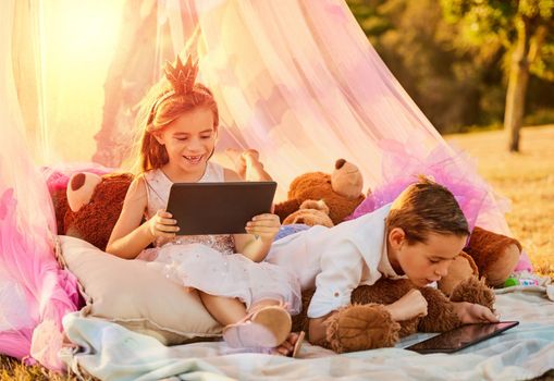 The new age taking technology outdoors with ease. Shot of an adorable little brother and sister using tablets outdoors.