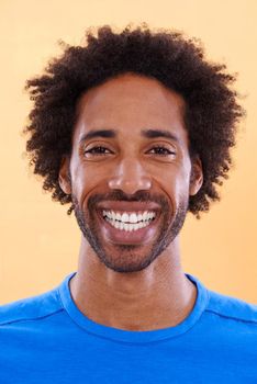 Showing off his brightest smile. A handsome young black man against a orange background.
