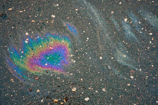 Rainbow gasoline oil spill on the pavement as a texture or background.