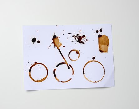 white sheet of paper with brown prints from the bottom of the cup with coffee, blots and splashes