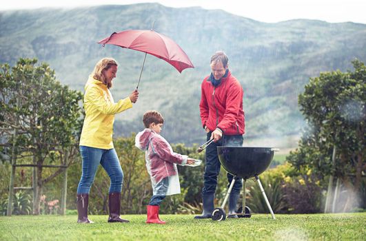 Shot of a family having a barbecue outside in rainy weather.