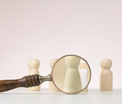 figurines of men on a white table and magnifying glass. Concept of searching for employees in the company, recruiting personnel, identifying talented