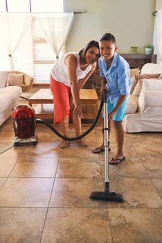 Hes quite helpful around the house. Portrait of a mother and son vacuuming the floor.