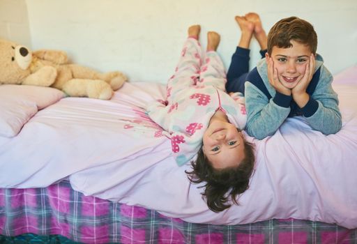 They share a special sibling bond. Shot of two young siblings lying down together on a bed at home.