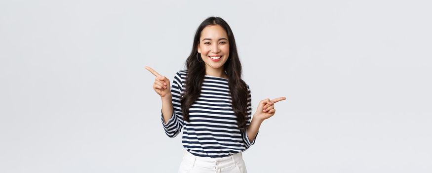 Lifestyle, beauty and fashion, people emotions concept. Indecisive cute korean girl need help with choice, pointing fingers sideways, showing left and right products, making decision