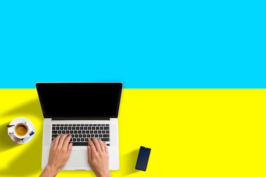 Visit Ukraine concept for your web banner or print materials. Top view of a laptop, coffee cup on Ukraine national flag. Flat style travel planninng website header.