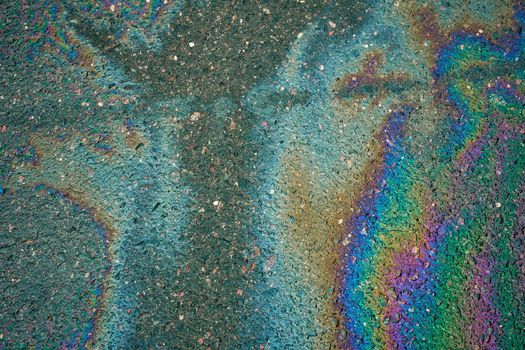 Rainbow gasoline oil spill on the pavement as a texture or background. Environmental pollution concept