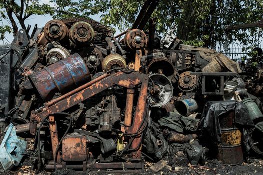 Many old rusty old car wheel axles, car shaft and used engines at the junk yard for sale.