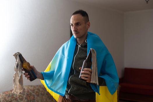 man with flag of ukraine with molotov cocktail in room