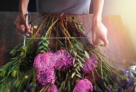 Flowers bring color to your life. Cropped shot of a pretty floral bouquet being completed on a wooden counter top.