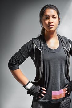 Focused on fitness. Portrait of a fit young woman in sports clothing posing against a gray background.