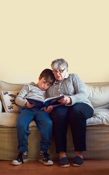 Its their favourite book to enjoy together. Shot of a grandmother reading a book to her grandson at home.