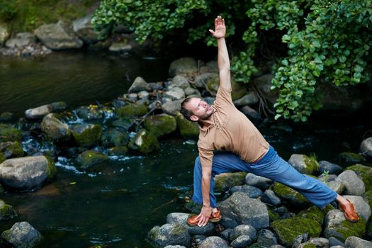 Shot of a handsome man doing yoga stretches outdoors.