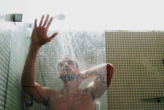 The shower is a great place to cool off. Cropped shot of a handsome young man having a refreshing shower at home.