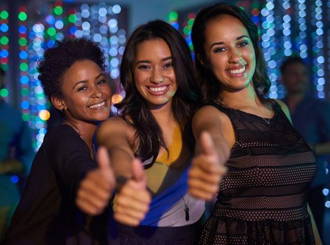 Good times in the club. Portrait of a group of young ladies showing thumbs up while partying in a club.