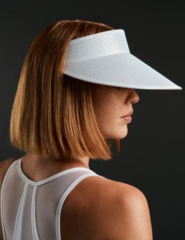 I advise you to wear your visor. Cropped shot of a sporty young woman wearing a sun visor against a dark background.