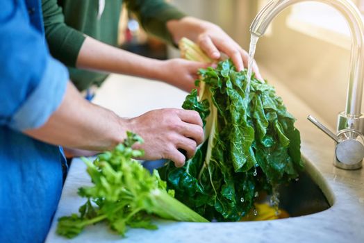 Making sure their produce is washed and ready to eat. Closeup shot of a couple washing spinach in their kitchen sink.