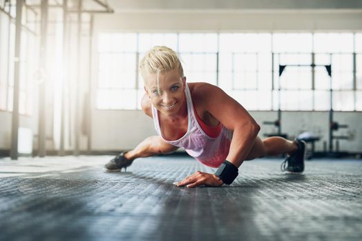 Excuses dont burn calories. Shot of a young attractive woman doing push ups with one hand at the gym.