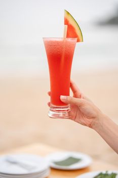 Glass of watermelon juice with blur ocean background.
