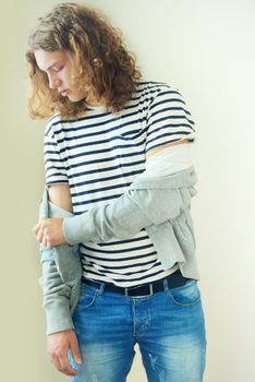 Tailoring his own style. Casual young man with long, curly hair.