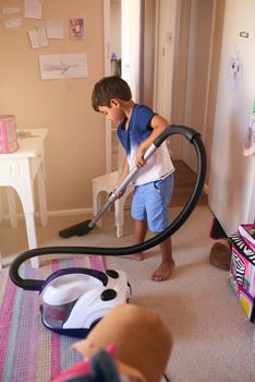Tidy up time. Shot of a little boy vacuuming his bedroom at home.