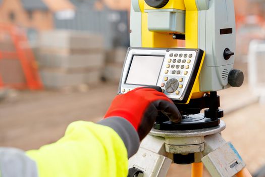Site engineer in hi-viz working on house building construction site using modern surveying equipmen
