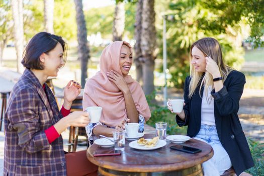 Cheerful multiracial women having coffee break
