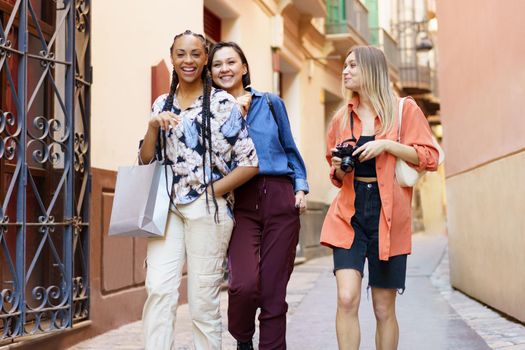 Joyful multiracial females strolling together after shopping