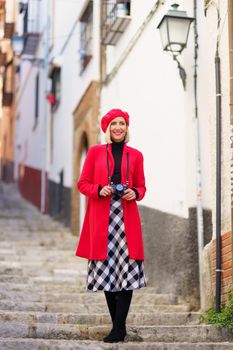 Fashionable lady standing on steps near aged building during vacation