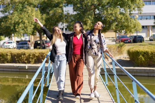 Positive diverse women walking on footbridge