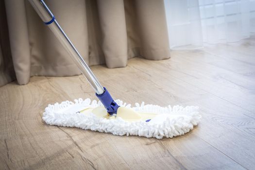 Modern white mop cleaning a wooden floor