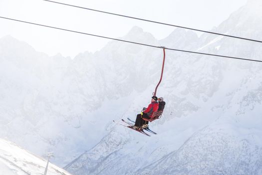 DOMBAI, RUSSIA - JANUARY 3, 2014: People are lifting on ski lift high up in Caucasus mountains