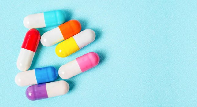 Colorful capsules (pills) on a blue background. Medical background.